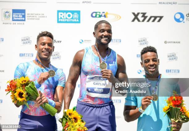 Athletes Justin Gatlin of the US, Paulo Andre de Oliveira of Brazil and Isiah Young of the US pose on the podium after the men's 100m final of the...