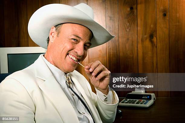 smiling cowboy businessman with toothpick - cowboy bolo tie stock pictures, royalty-free photos & images