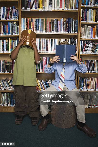 boys covering faces with books - school tie stockfoto's en -beelden