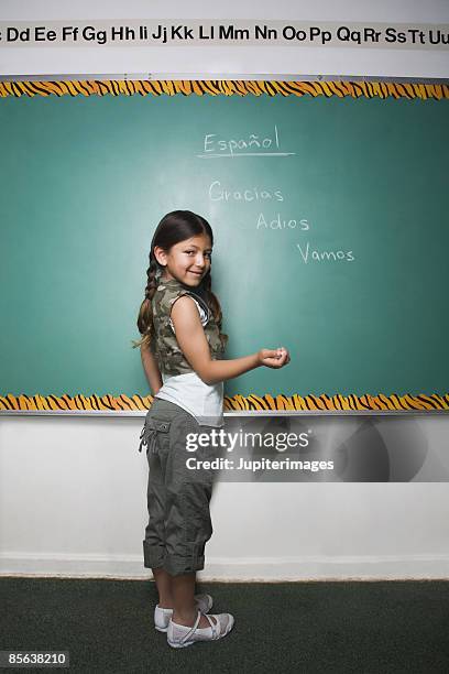 girl writing in spanish on chalkboard - bilingual stock pictures, royalty-free photos & images