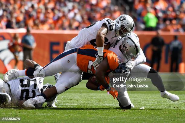 Anderson of the Denver Broncos is tackled by Erik Harris and Shalom Luani of the Oakland Raiders in the first quarter. The Denver Broncos hosted the...