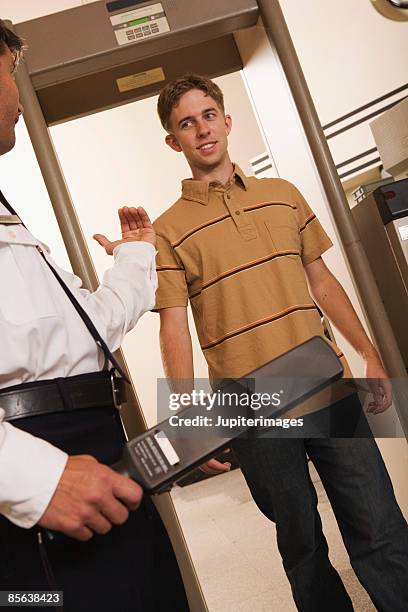 airport security officer directing man through security checkpoint - body scanner stock pictures, royalty-free photos & images