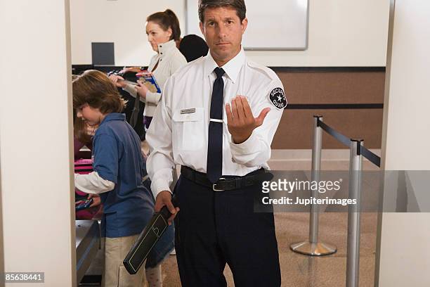 airport security officer directing passengers through security checkpoint - airport security foto e immagini stock