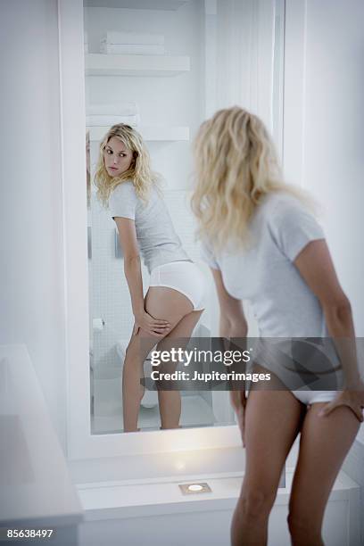 woman looking critically at self in mirror - woman-looking-into-mirror-full-body stock pictures, royalty-free photos & images