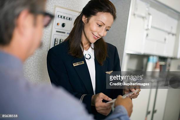stewardess greeting passengers on airplane - flight attendants stock-fotos und bilder