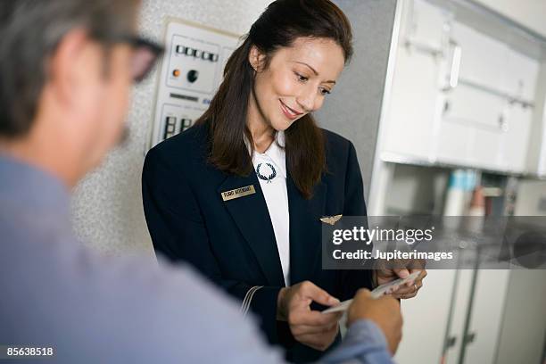 stewardess greeting passengers on airplane - tripulación fotografías e imágenes de stock