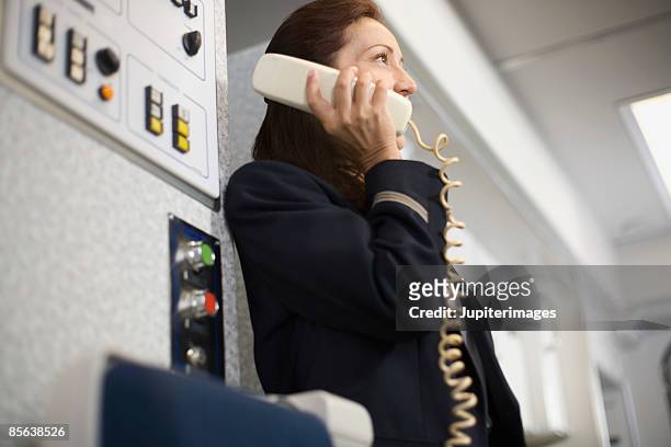 stewardess instructing passengers on airplane over the loudspeaker - flight attendants stock-fotos und bilder