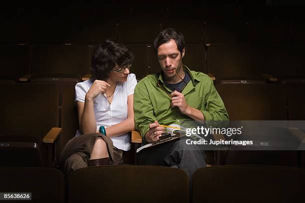 man and woman looking at clipboard in theater - critic photos et images de collection