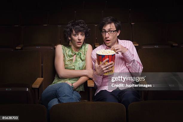 scared couple in movie theatre - couple in cinema seats stock pictures, royalty-free photos & images