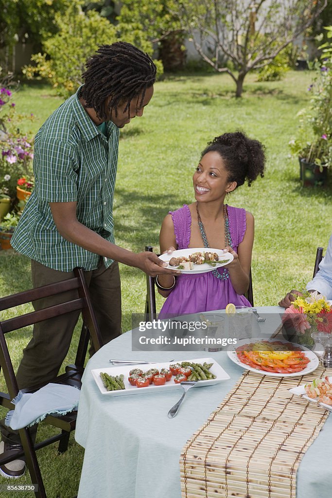 Man serving food to woman at outdoor table