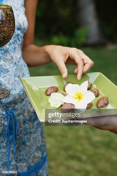 woman taking chocolate macadamia nut - macadamia stock pictures, royalty-free photos & images