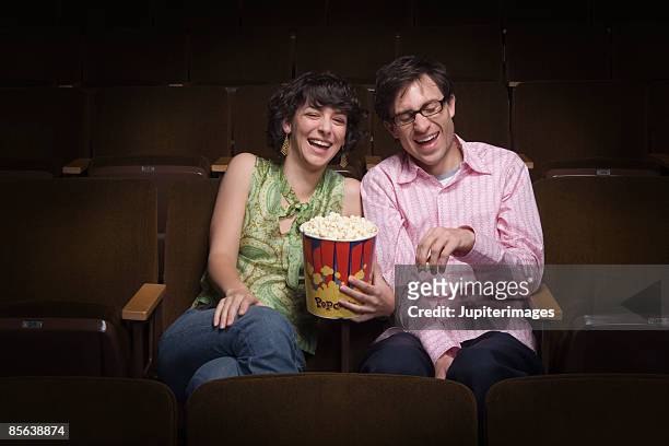 couple laughing in movie theatre - auditoria stockfoto's en -beelden