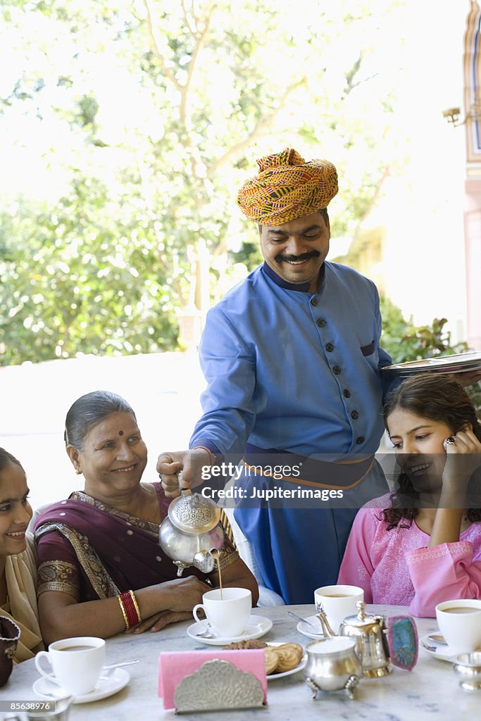 Butler pouring tea for women