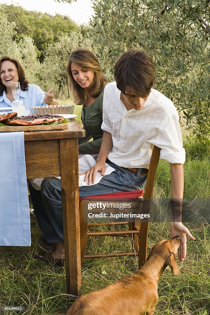 Family feeding dog at table , Montevettolini , Italy