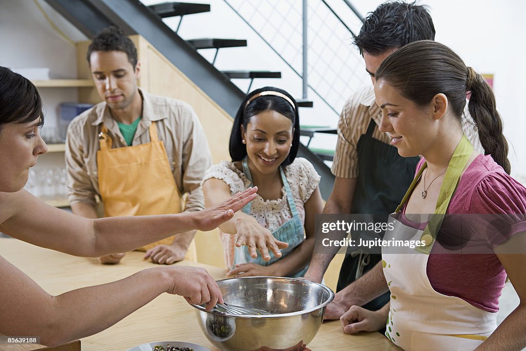 Adults watching woman whisking