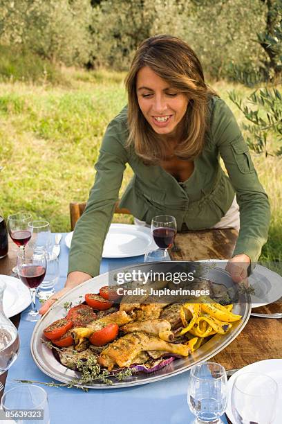 woman passing grilled chicken and vegetables platter - gelbe paprika stock-fotos und bilder