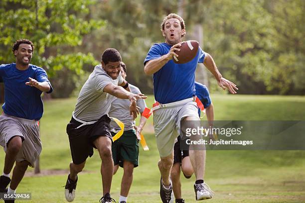 men playing flag football together - chasing stockfoto's en -beelden