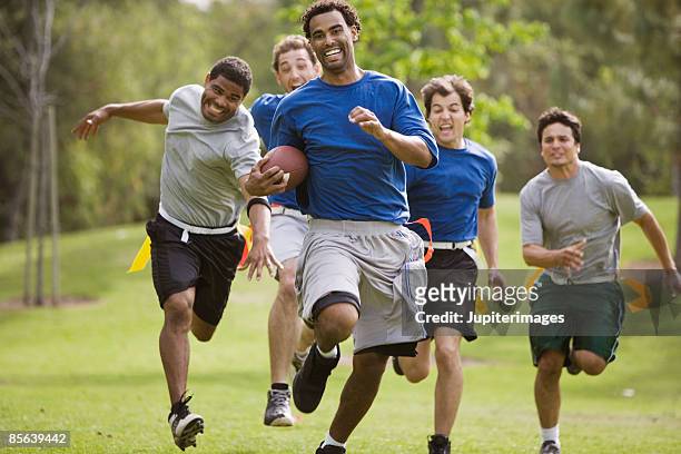 men playing flag football together - rush american football stock pictures, royalty-free photos & images
