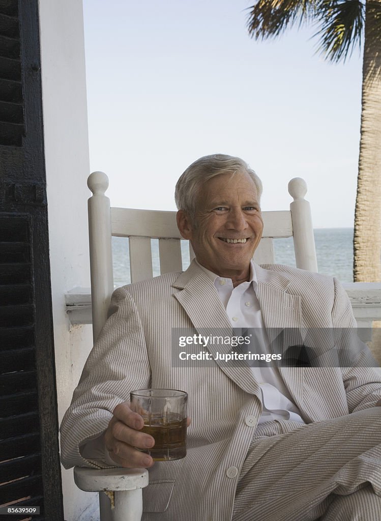 Smiling man on balcony with cocktail