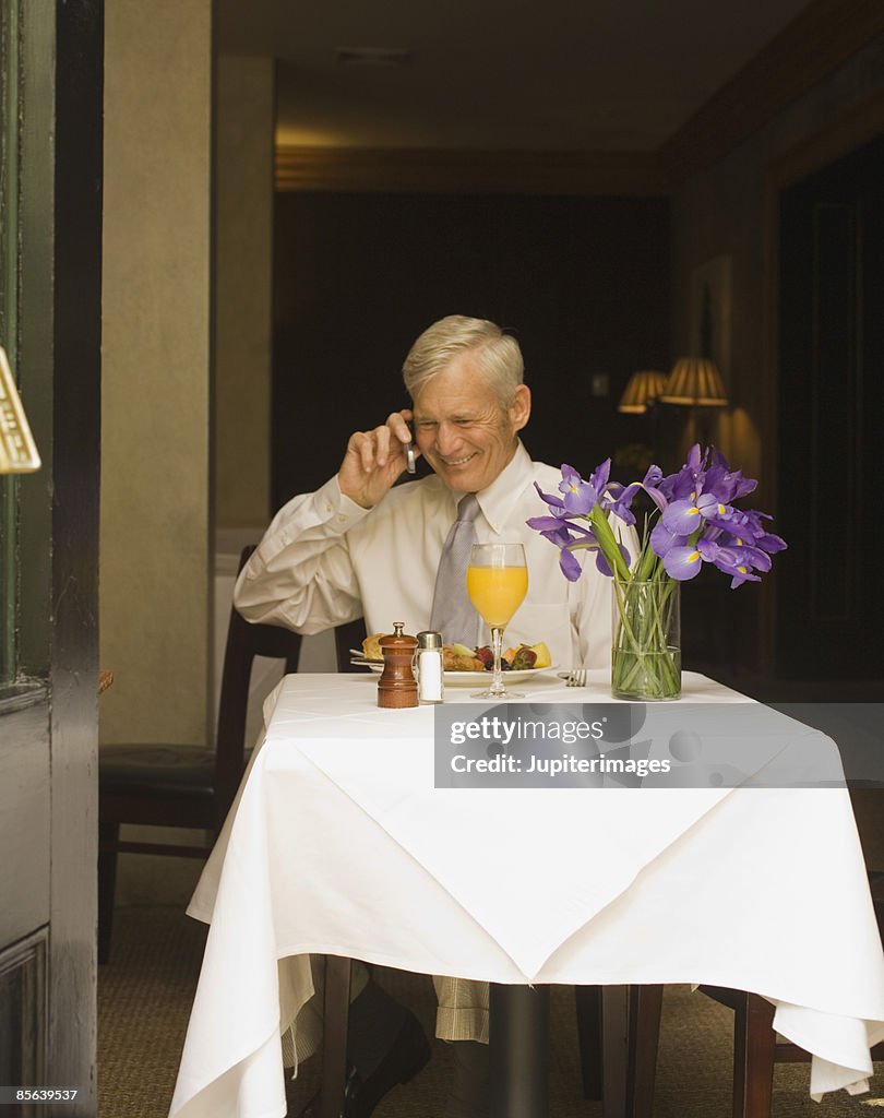 Man talking on cell phone at cafe table