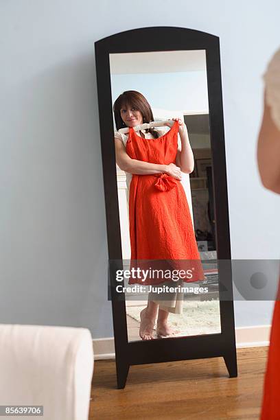 middle-aged woman looking in mirror - red dress stock pictures, royalty-free photos & images