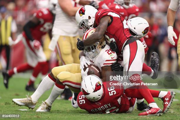 Running back Carlos Hyde of the San Francisco 49ers is tackled by inside linebacker Karlos Dansby, cornerback Justin Bethel and defensive end Frostee...