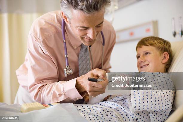 doctor signing boy's cast - boy broken arm stock pictures, royalty-free photos & images