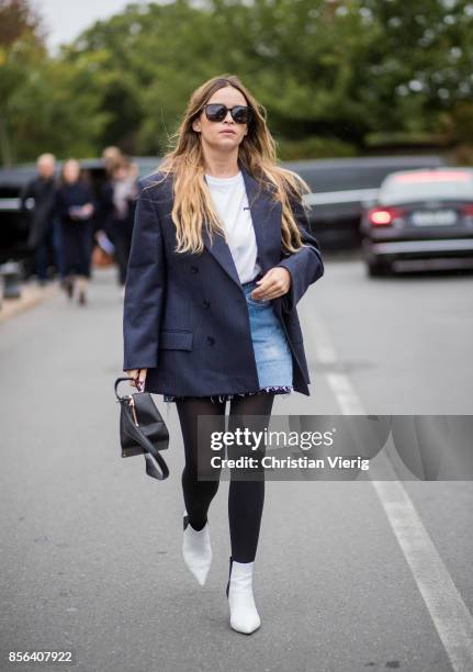 Miroslava Duma wearing navy blazer, denim mini skirt, tights, white boots seen outside Balenciaga during Paris Fashion Week Spring/Summer 2018 on...