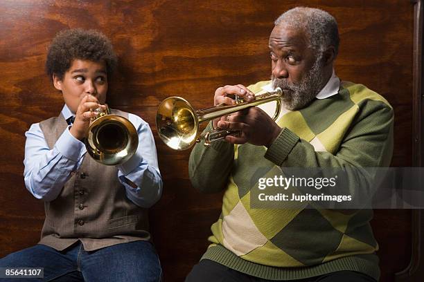 preteen boy and grandfather playing trumpet together - jazz music stockfoto's en -beelden