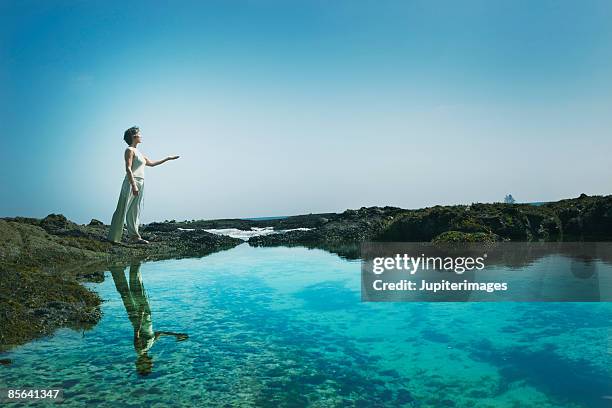 woman standing at water's edge - new age stock pictures, royalty-free photos & images