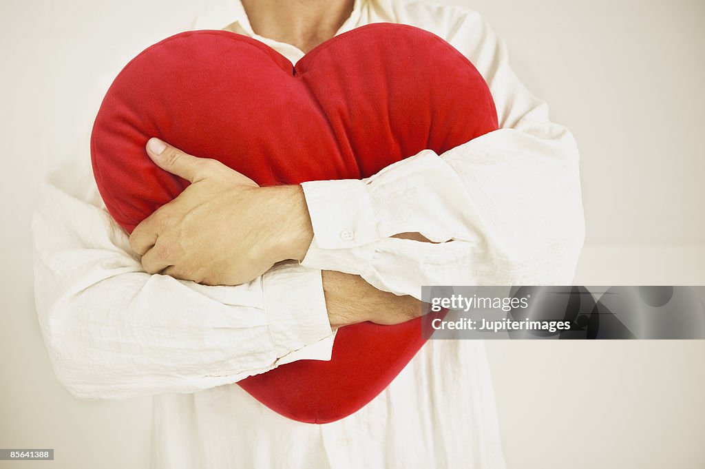 Man hugging heart-shaped pillow