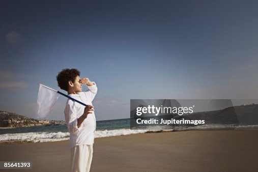 Boy holding net and shielding eyes Boy holding net and shielding eyes