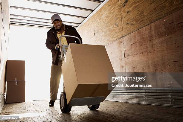 man loading boxes onto truck - pushing fotografías e imágenes de stock