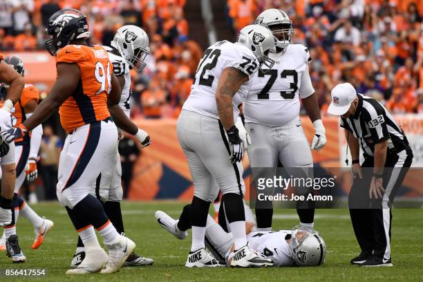 Derek Carr of the Oakland Raiders lies on the turf after being injured by Adam Gotsis of the Denver Broncos during the third quarter on Sunday,...