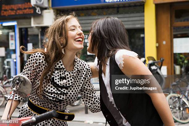 woman sitting on scooter embracing friend - hi imagens e fotografias de stock