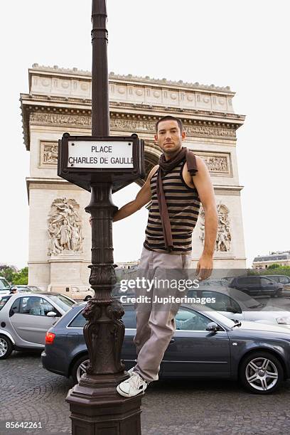 man standing on street sign in front of arc de triomphe,  paris,  france - triomfboog stockfoto's en -beelden