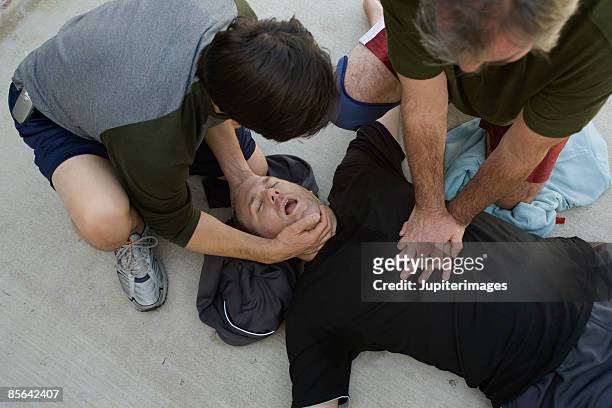 men doing cpr on another man - unconscious fotografías e imágenes de stock
