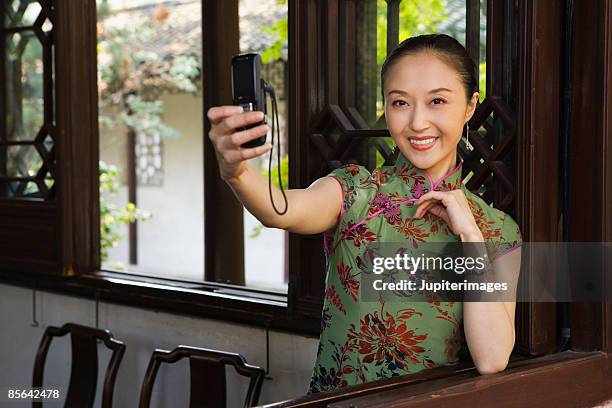 woman taking picture with camera phone - cheongsam stock pictures, royalty-free photos & images