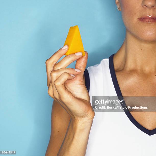 woman holding piece of cheese - cheeses stock-fotos und bilder