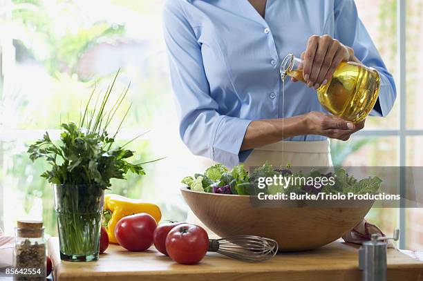 woman making salad with dressing - salad foto e immagini stock