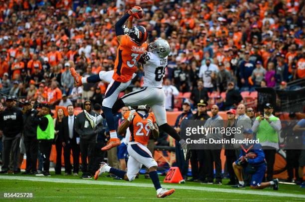 Strong safety Justin Simmons of the Denver Broncos intercepts a deep pass intended for wide receiver Amari Cooper of the Oakland Raiders as free...