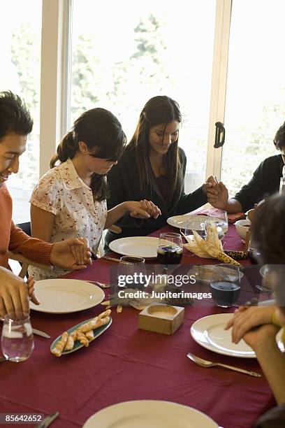 friends holding hands at dining table - saying grace stock pictures, royalty-free photos & images