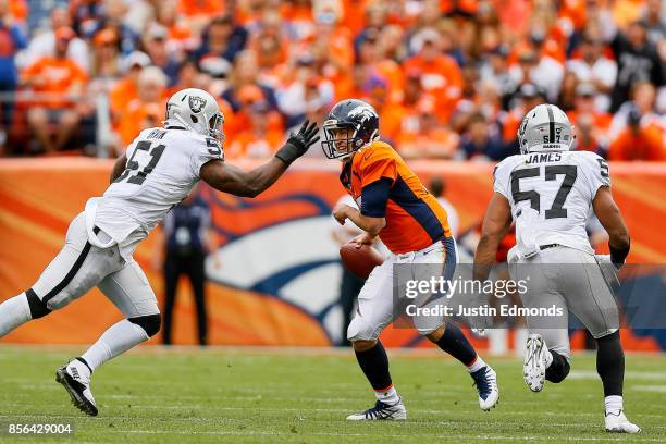 Quarterback Trevor Siemian of the Denver Broncos tries to avoid a hit by outside linebacker Bruce Irvin of the Oakland Raiders during a game at...