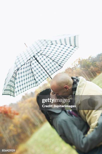 couple kissing under umbrella - couples kissing shower photos et images de collection