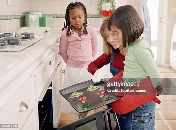 woman and girls taking cookies from oven - hot filipina women stockfoto's en -beelden