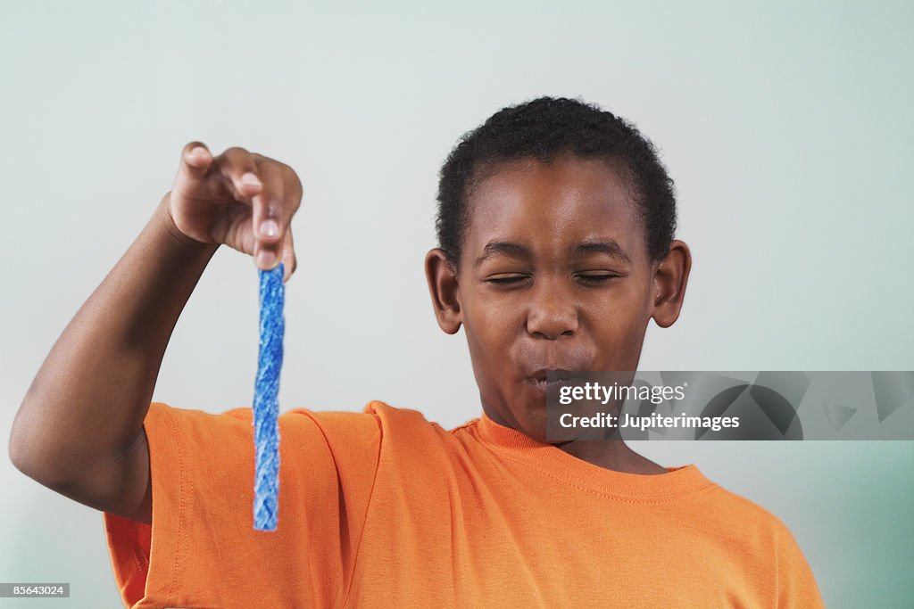 Boy holding blue candy and making face