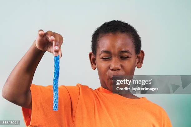 boy holding blue candy and making face - 酸っぱい ストックフォトと画像