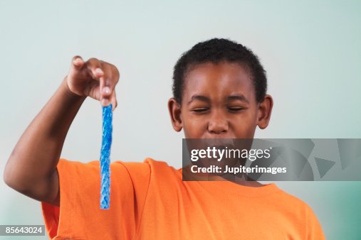 Boy holding blue candy and making face Boy holding blue candy and making face