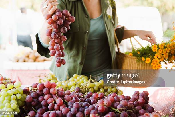 woman with grapes at farmer's market - mercato di prodotti agricoli foto e immagini stock