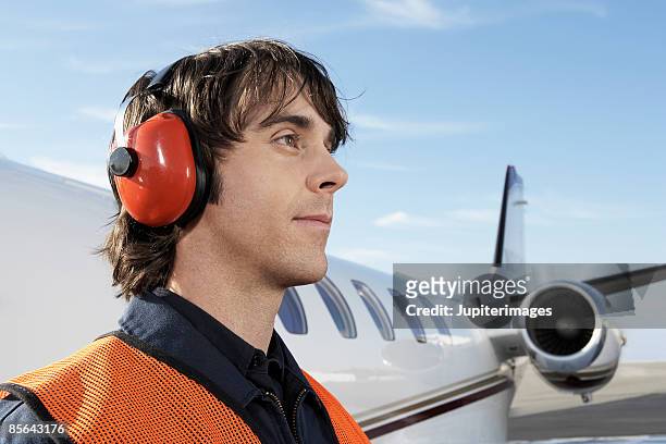 airport worker with airplane - orejeras fotografías e imágenes de stock